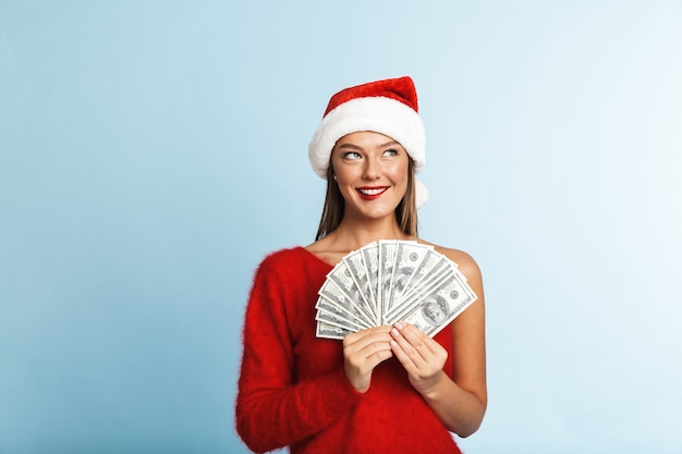 Jovem alegre com chapéu de Papai Noel, mostrando notas de dinheiro