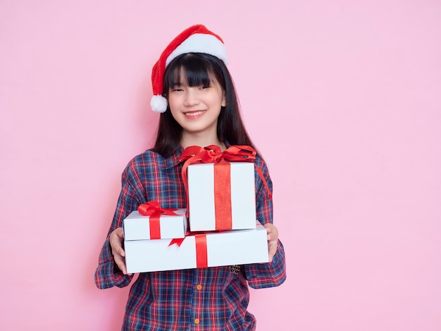 Jovem alegre com chapéu de Papai Noel segurando caixas de presente rosa