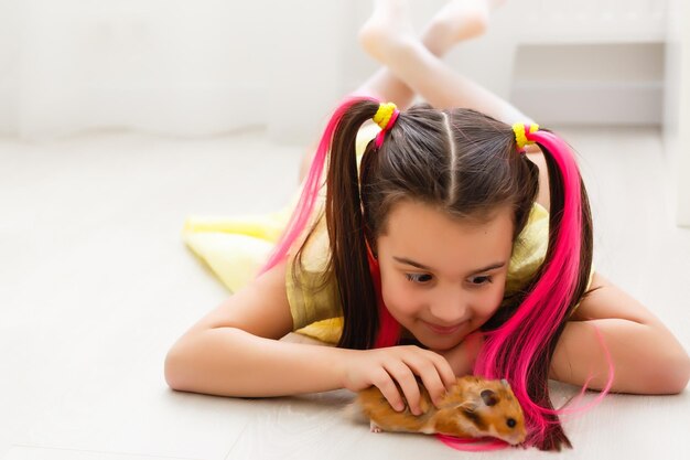 Jovem alegre com um hamster de estimação usando o computador portátil, estudando através do sistema de e-learning online em casa. Aprendizagem à distância ou à distância