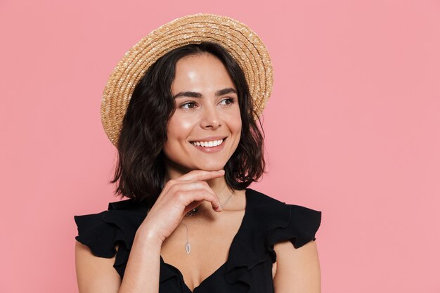 Jovem alegre com um vestido de verão em pé, isolada na parede rosa, olhando para longe