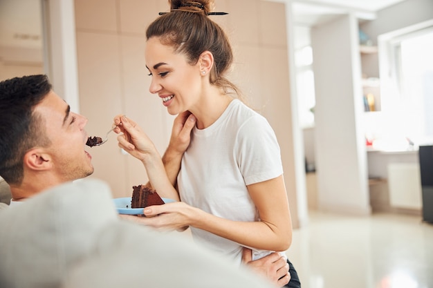 Jovem alegre dando bolo de chocolate para um homem