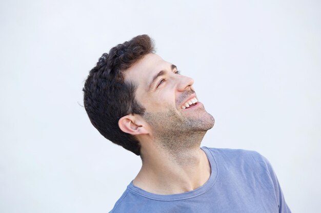 Jovem alegre de perto sorrindo e olhando para longe contra um fundo branco