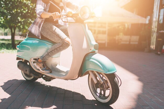 Jovem alegre dirigindo scooter na cidade