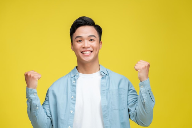 Jovem alegre e feliz posando isolado em fundo amarelo brilhante