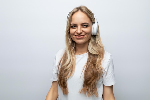 Jovem alegre em fones de ouvido brancos ouvindo podcasts em fundo branco