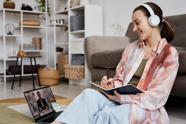 Jovem alegre em fones de ouvido e roupas casuais ouvindo seu tutor