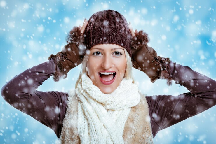 Foto jovem alegre em roupas de inverno com as mãos na cabeça, regozijando-se na primeira neve.