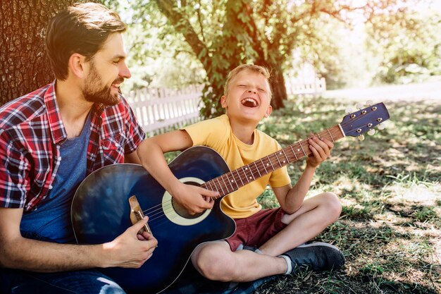 Jovem alegre está segurando o violão e tocando nele