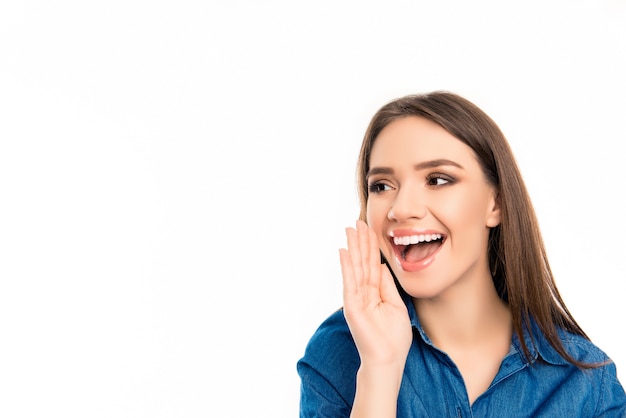 Jovem alegre feliz contando um segredo sobre fundo branco