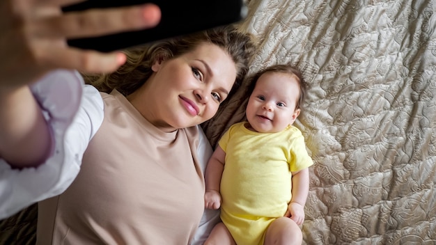 Jovem alegre mãe com cabelo encaracolado tira foto da filha