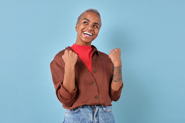 Foto jovem alegre mulher afro-americana felizmente aperta os punhos está no estúdio