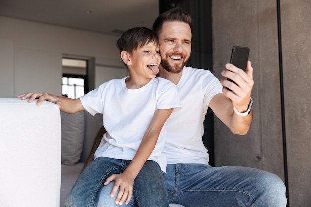 Jovem alegre, pai, pai, usando telefone celular com o filho