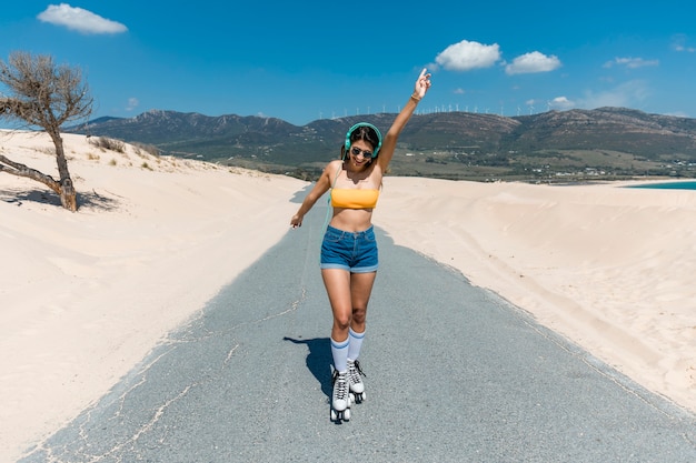 Jovem alegre patins na estrada de areia