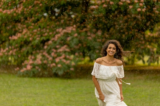 Jovem alegre pega pela chuva de verão no parque