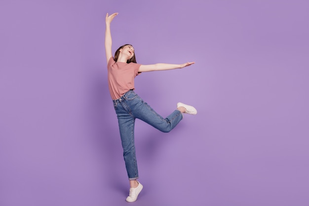 Jovem alegre posando dançando isolada em um fundo violeta