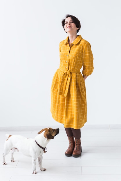 Jovem alegre posando em um vestido amarelo com seu amado cachorro Jack Russell Terrier em pé