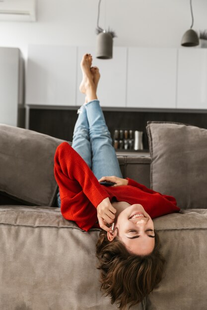 Jovem alegre relaxando em casa, ouvindo música com fones de ouvido sem fio