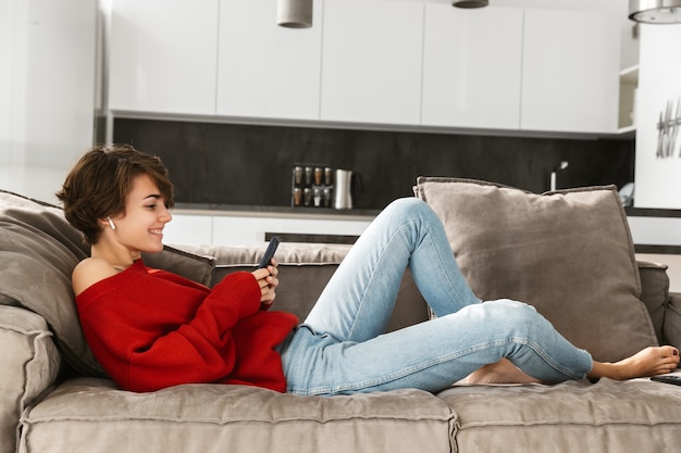 Jovem alegre relaxando em casa, ouvindo música com fones de ouvido sem fio