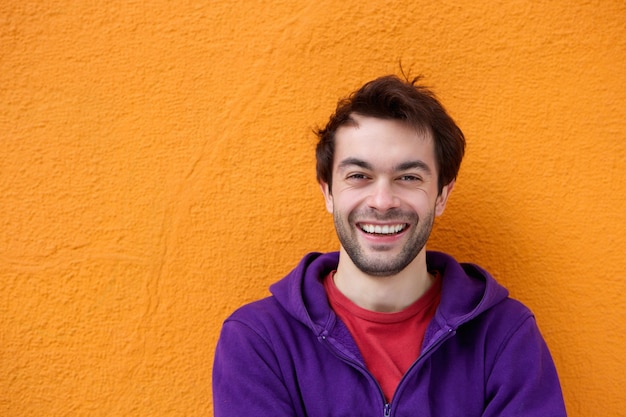 Jovem alegre sorrindo em fundo laranja