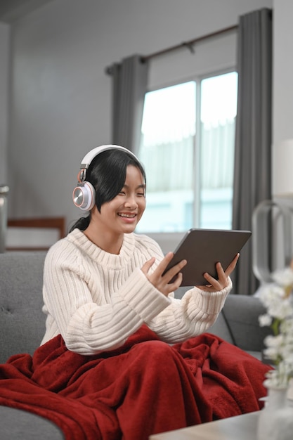 Jovem alegre usando fone de ouvido e assistindo algo engraçado no tablet digital