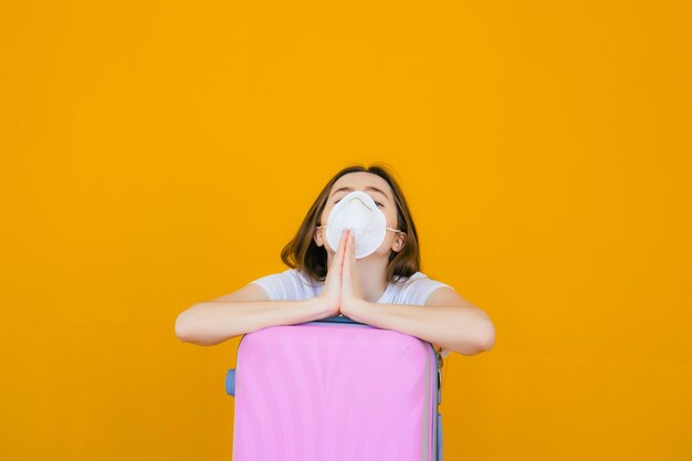 jovem alegre vestida com roupas de verão e óculos de sol em pé com uma mala