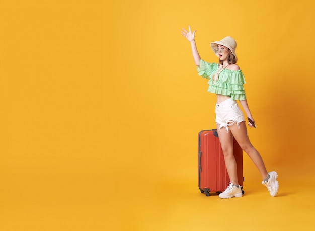 Jovem alegre vestida com roupas de verão em pé com uma mala