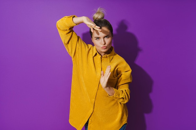 Jovem alegre vestindo camisa amarela dançando contra fundo roxo