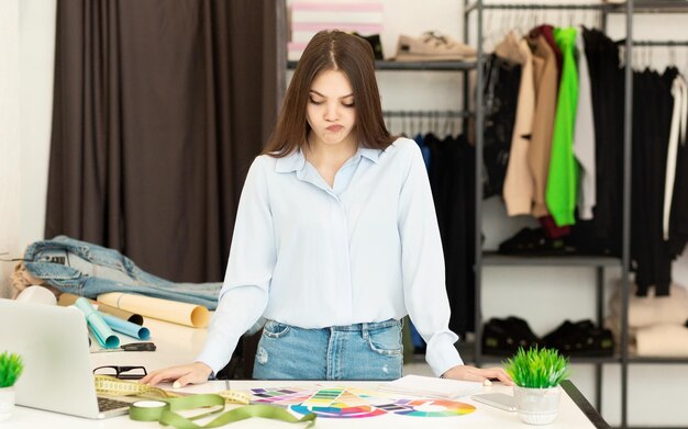 Jovem alfaiate selecionando cor para camisa nova e tendo dúvidas no atelier
