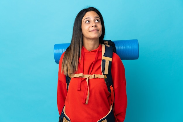 Foto jovem alpinista com mochila e olhando para cima