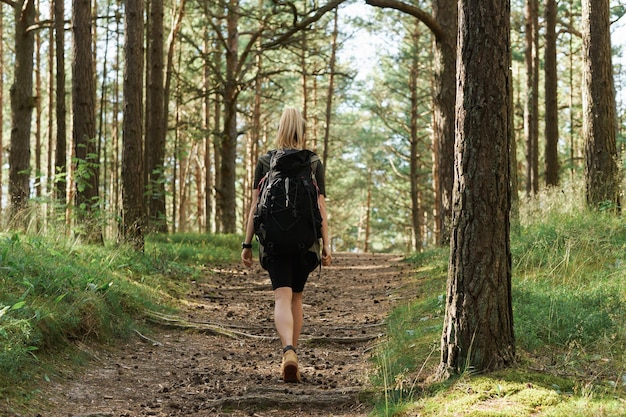 Jovem alpinista com mochila grande na floresta verde