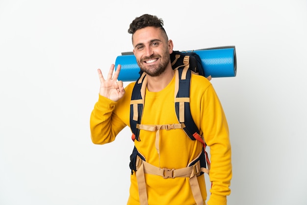 Jovem alpinista com uma grande mochila sobre uma parede isolada, mostrando um sinal de ok com os dedos