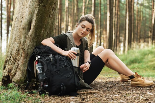 Jovem alpinista durante uma pequena parada sentada na floresta verde