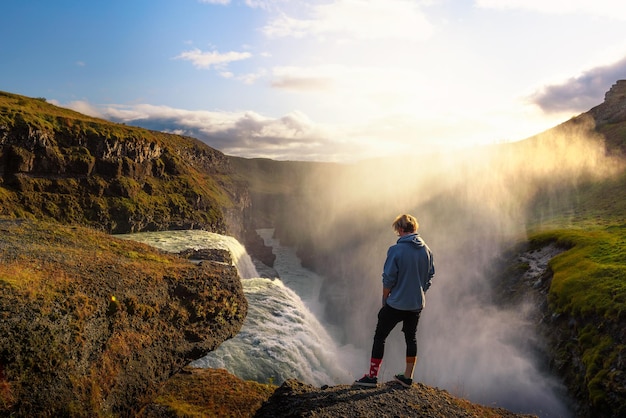 Jovem alpinista em pé à beira da cachoeira gullfoss na islândia