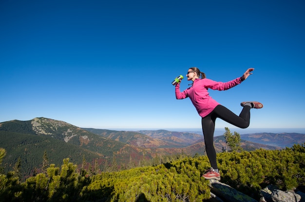 Jovem alpinista feminina feliz no topo da montanha