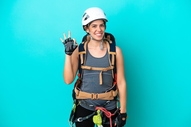 Jovem alpinista italiana isolada em fundo azul, mostrando sinal de ok com os dedos