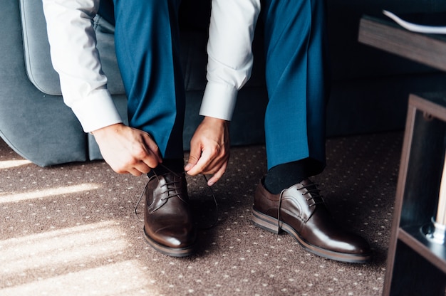 Foto jovem amarrar sapatos elegantes dentro de casa