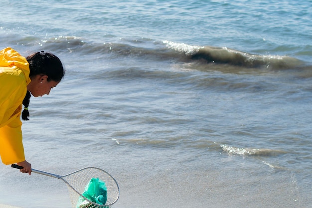 Jovem ambientalista coletando plásticos na praia