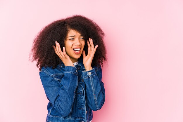 Jovem americana Africano grita alto, mantém os olhos abertos e mãos tensas.