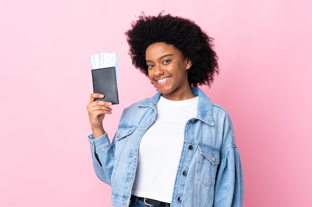 Jovem americana Africano na parede rosa feliz em férias com bilhetes de avião e passaporte