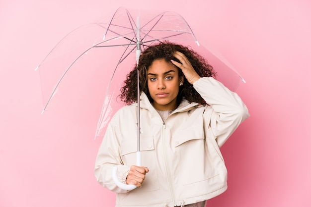 Jovem americana Africano segurando um guarda-chuva estar chocado, ela se lembrou de importante reunião.