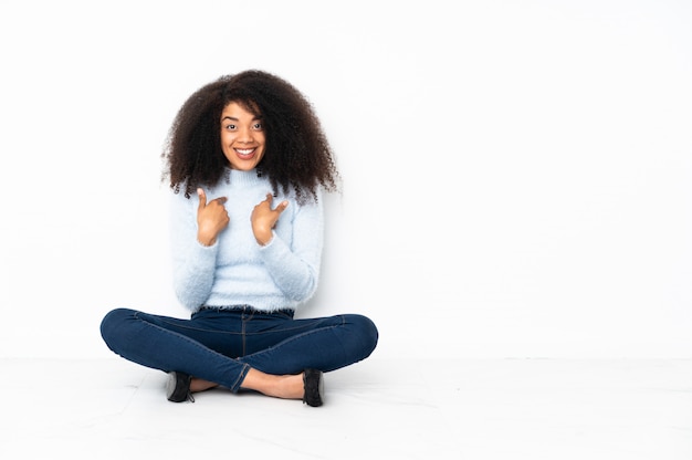 Jovem americana Africano, sentada no chão com expressão facial de surpresa