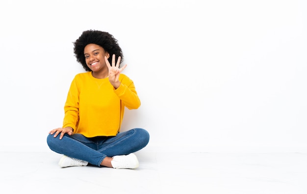 Jovem americana Africano sentado no chão feliz e contando quatro com os dedos