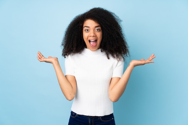 Jovem americana Africano sobre parede com expressão facial chocado