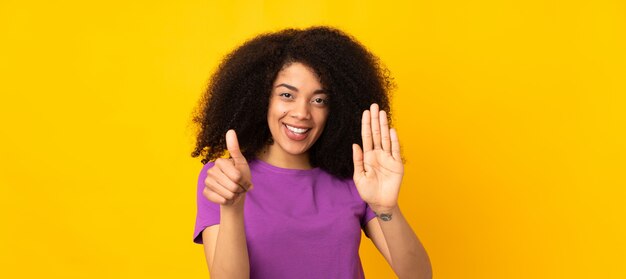 Jovem americana africano sobre parede isolada, contando seis com os dedos