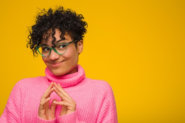 Jovem americana africano vestindo um suéter rosa, inventando o plano em mente, criando uma idéia.