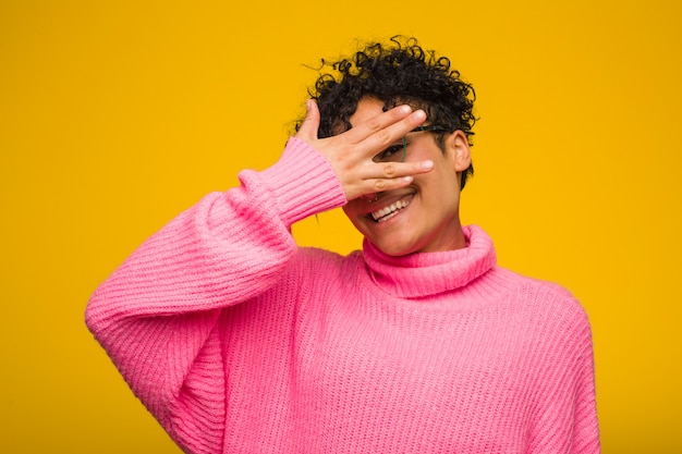 Jovem americana Africano vestindo uma blusa rosa piscar para a câmera através dos dedos, rosto de vergonha coberta.