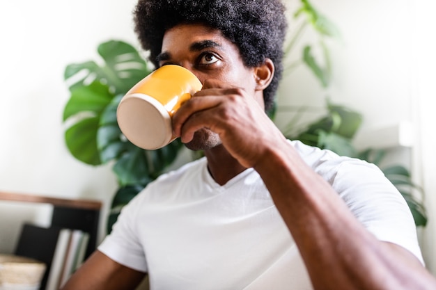 Foto jovem americano africano bebe café da manhã sozinho em casa. no conceito de casa.