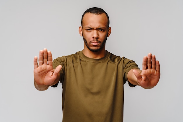 Foto jovem americano africano gesticulando stop com a mão sobre a parede cinza claro