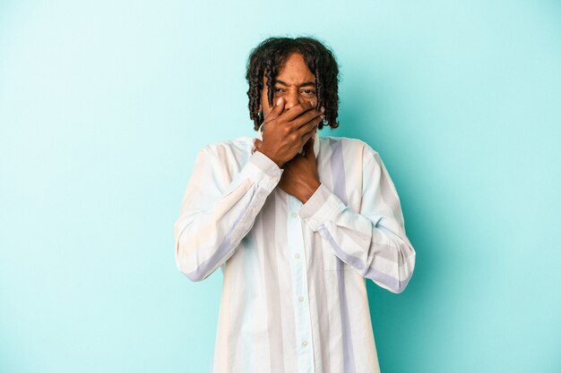 Jovem americano africano isolado em um fundo azul sofre de dor na garganta devido a um vírus ou infecção.