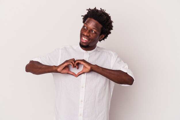 Jovem americano africano isolado no fundo branco, sorrindo e mostrando uma forma de coração com as mãos.
